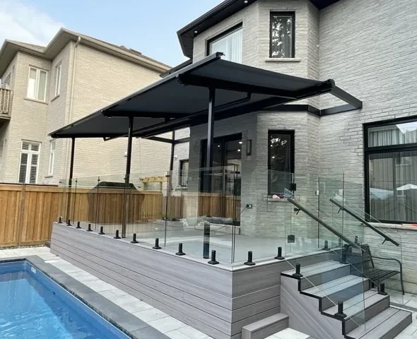 Black retractable awning extended over elevated pool deck with glass railing