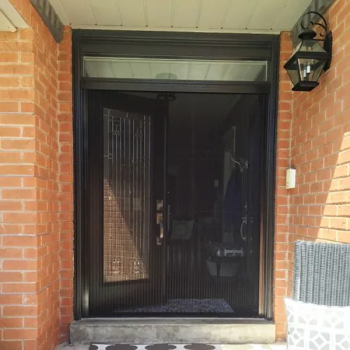 Dark vertical bug door screen covering brick-framed front entry door