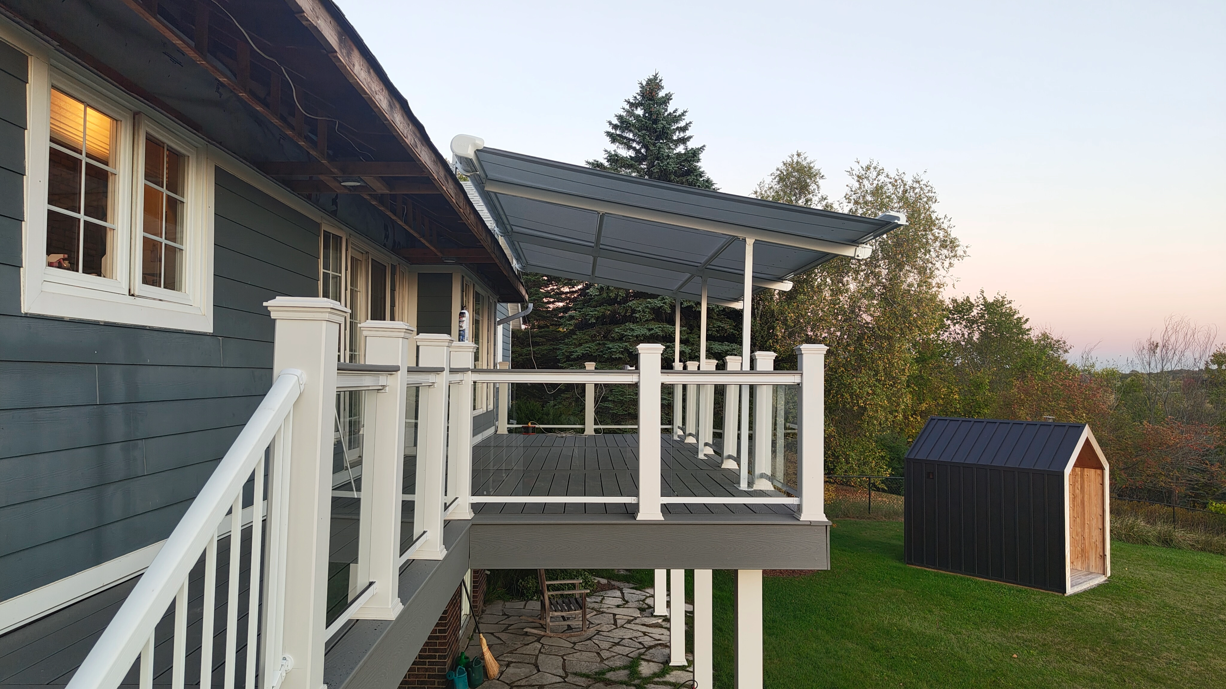 Fixed sloped aluminum awning covering elevated deck beside glass railing