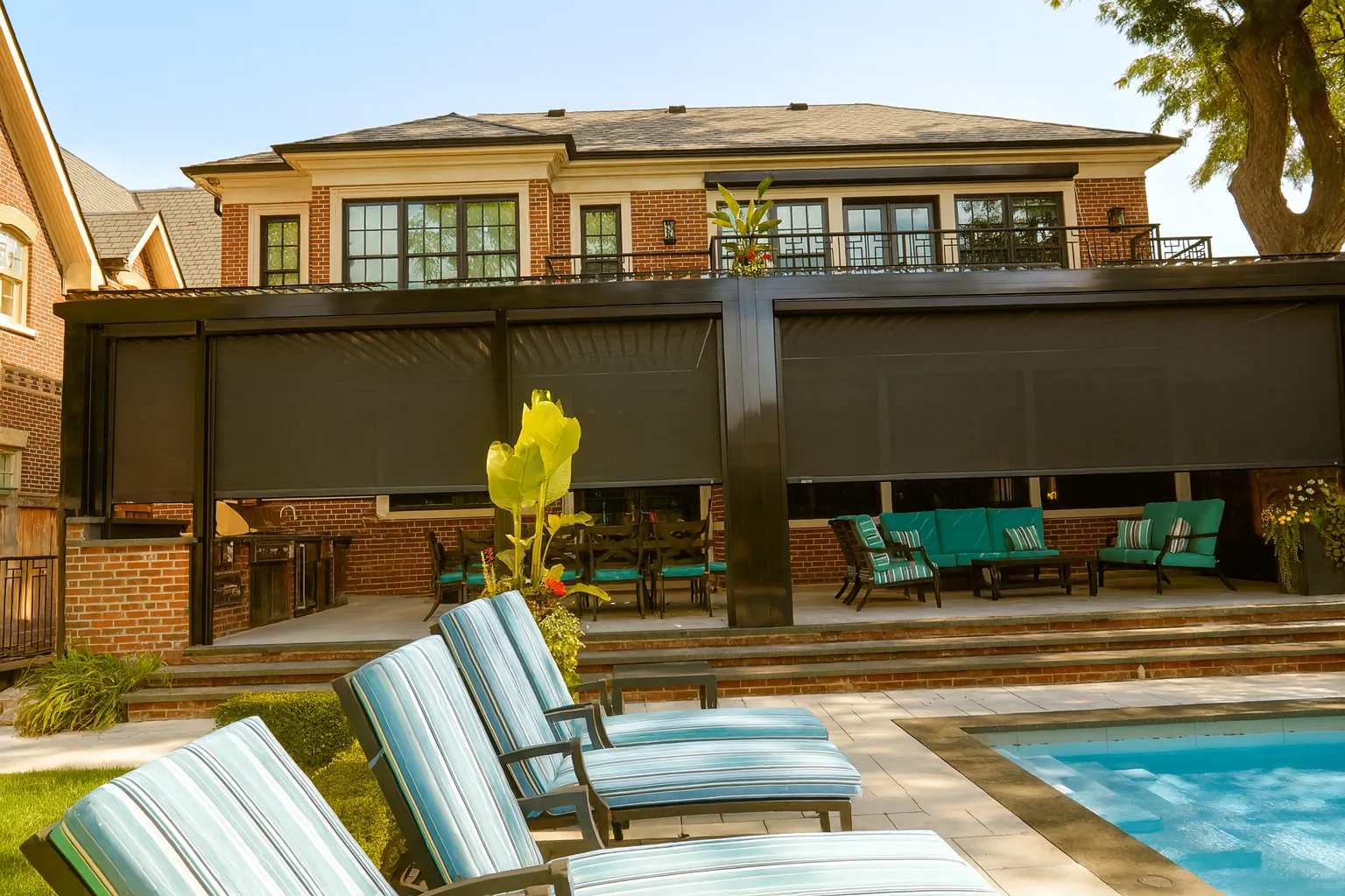 Louvered aluminum pergola on a large brick home, enclosed with dark motorized retractable screens over a poolside patio