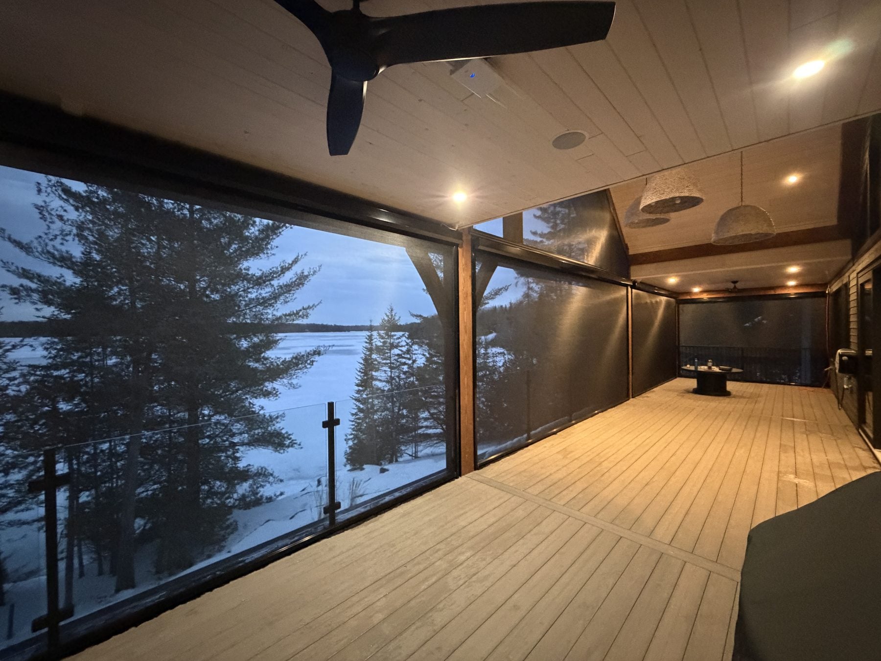 Covered lakeside deck at dusk enclosed by lowered motorized retractable screens