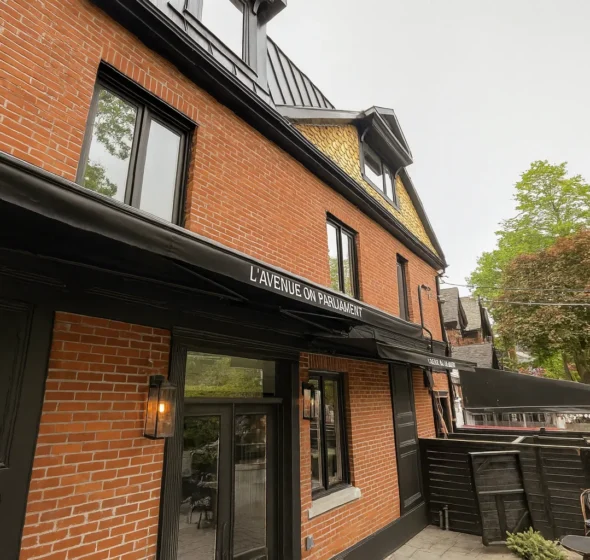 Black retractable awning extended along the brick facade of a restaurant patio